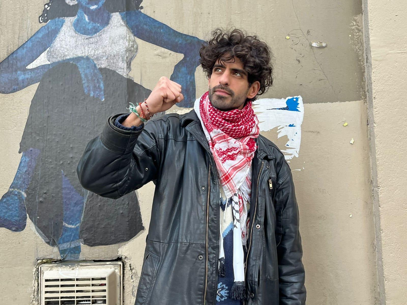 Nader Ayache pose dos à un mur. Il à le point levé et regarde vers le haut.